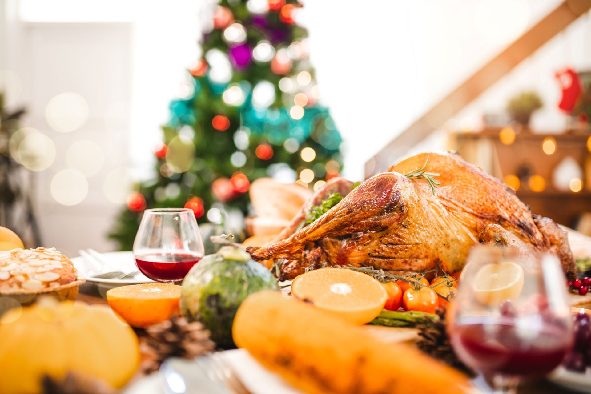 Roasted turkey on a Christmas dinner table with a decorated tree in the background